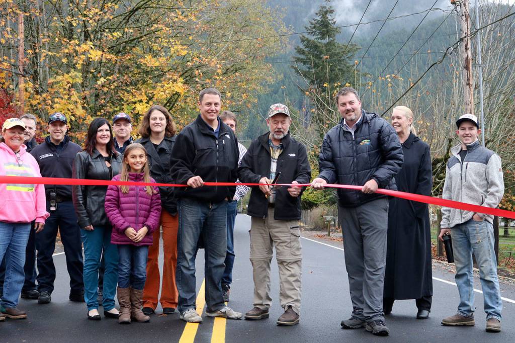 Tom Mohr, Ken Hearing, and Mark Rigos hold on to the ribbon along NE 12th Street, just outside of the Nursery at Mount Si. Evan Pappas/Staff Photo