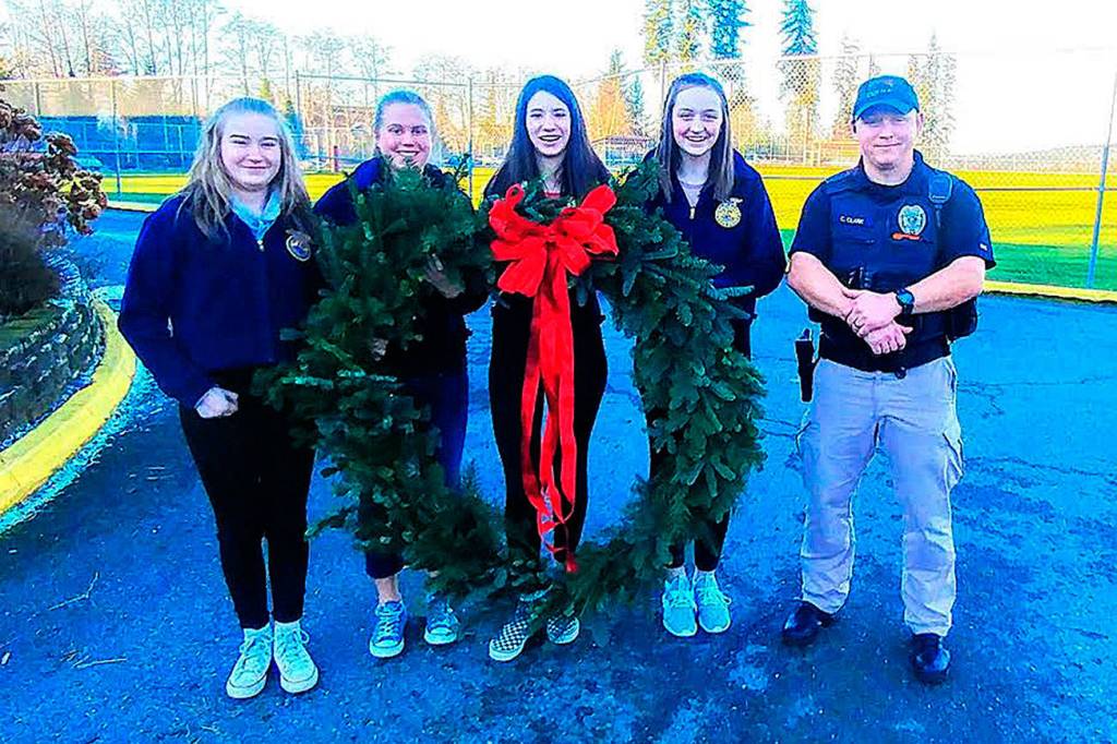 The 40-inch wreath was given to the Duvall Police Department for the third year in a row. From left: Elisabeth Anderson, Bethany Smith, Madison Rose, Emma Chaffin, Officer Cory Clark. Photo by Sarah Thomas