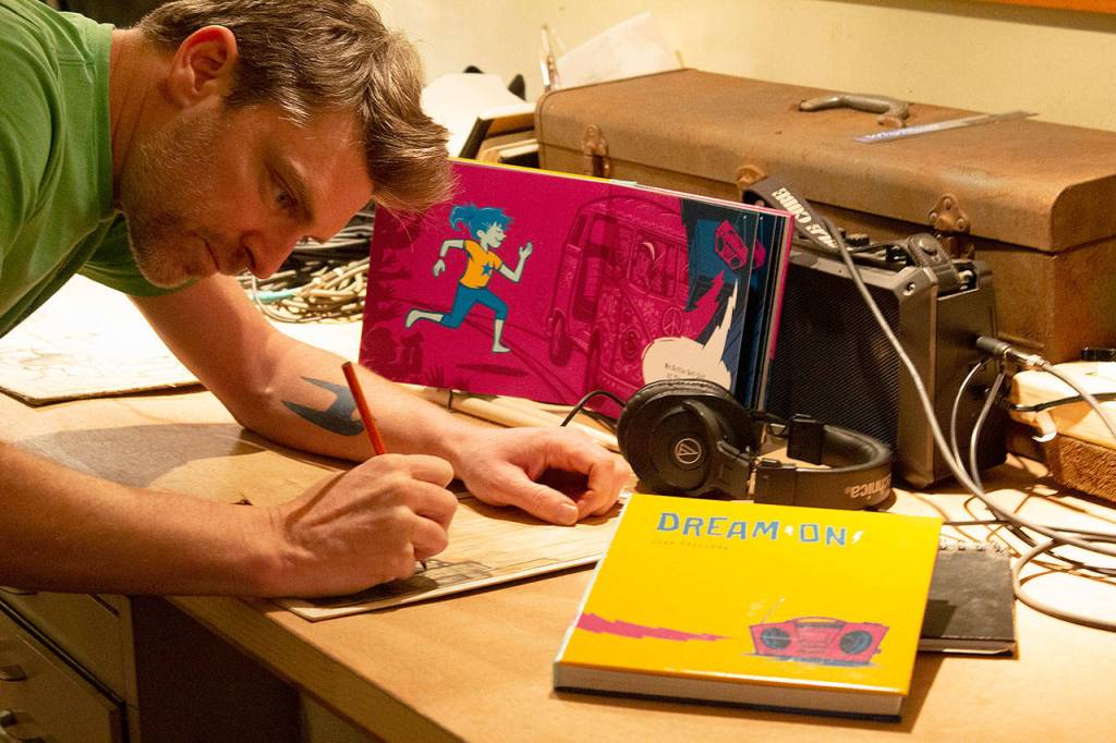 Josh Tuininga of North Bend sketches in his converted vintage Bluebird school bus art studio. Photo courtesy of Josh Tuininga