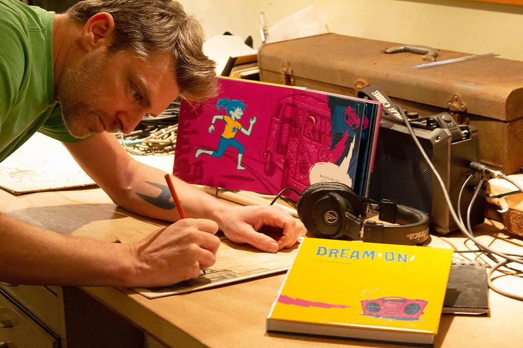 Josh Tuininga of North Bend sketches in his converted vintage Bluebird school bus art studio. Photo courtesy of Josh Tuininga