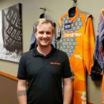 Dirtfishs media manager Trevor Wert stands against a wall of suits worn by professional Dirtfish racers. Drew Stuart/ Staff Photo