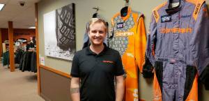 Dirtfishs media manager Trevor Wert stands against a wall of suits worn by professional Dirtfish racers. Drew Stuart/ Staff Photo