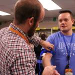 Opstad Elementary math teacher Ryan Vidos practices fastening a tourniquet to Opstad Elementary principal Ryan Hill. Madison Miller/staff photo.