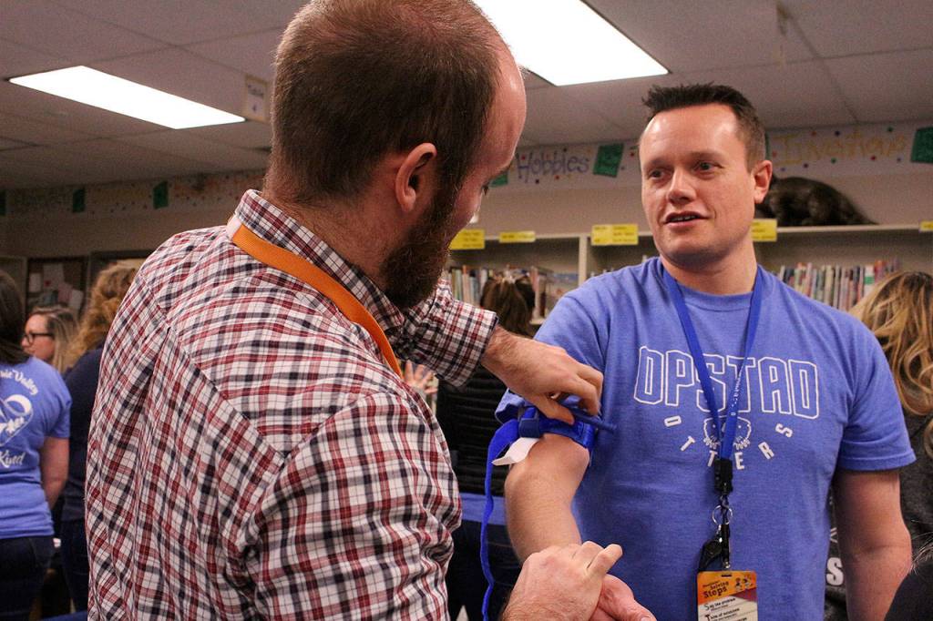 Opstad Elementary math teacher Ryan Vidos practices fastening a tourniquet to Opstad Elementary principal Ryan Hill. Madison Miller/staff photo.