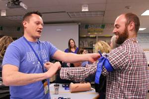 Opstad Elementary Schools principal Ryan Hill and math teacher Ryan Vidos practice using tourniquets as part of the Stop the Bleeds training. Madison Miller/staff photo.