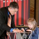 Magician Jeff Evans invites Audrey McDonald, 4, to the stage to prepare for a magic trick. After the recognition event, Evans performed his routine for the audience of volunteers and their families. Evan Pappas/Staff Photo