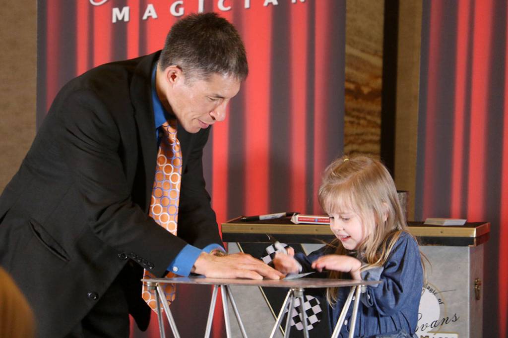 Magician Jeff Evans invites Audrey McDonald, 4, to the stage to prepare for a magic trick. After the recognition event, Evans performed his routine for the audience of volunteers and their families. Evan Pappas/Staff Photo