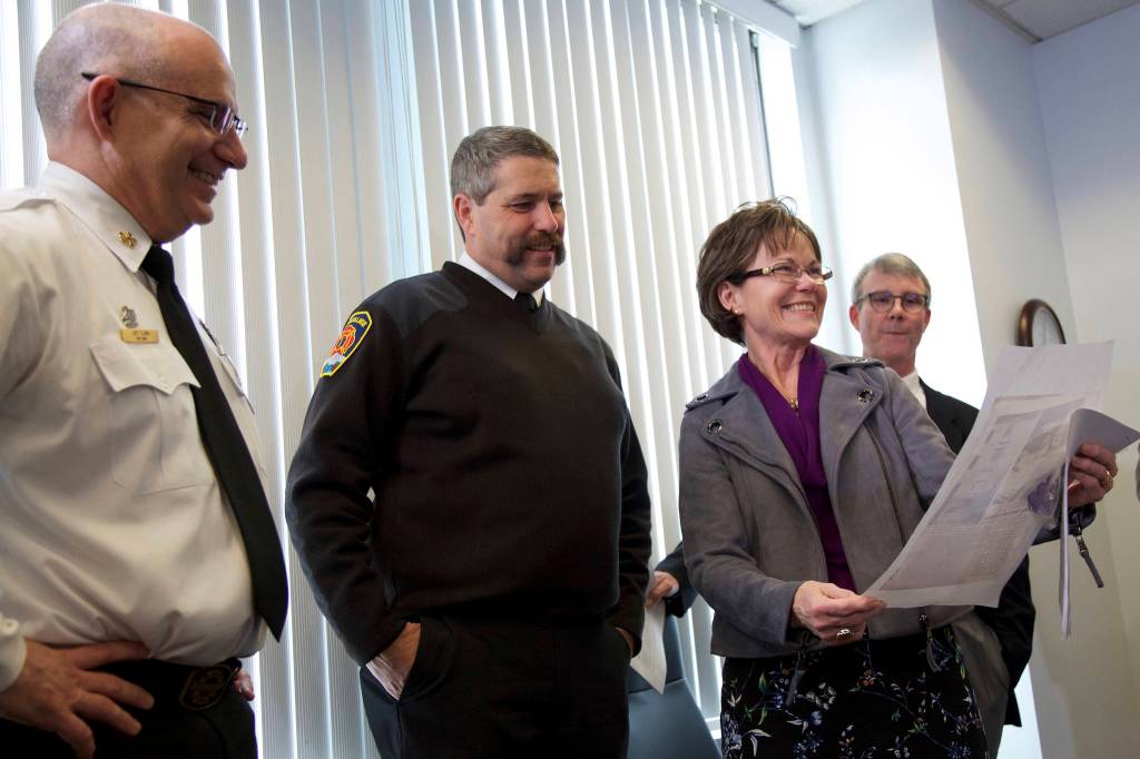 Ashley Hiruko/staff photo                                County Councilmember Kathy Lambert shows off a news article about a one-year-old girl who her father, a San Francisco police officer at the time, witnessed fall. From left: Eastside Fire & Rescue Chief Jeff Clark, Snoqualmie Fire Department Chief Mark Correira, Lambert, and Dr. Brian Johnston, chief of pediatrics at Harborview Medical Center.