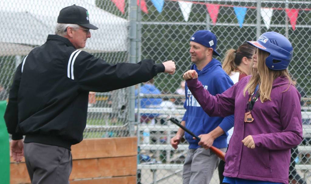 Olivia Corbin crosses home plate and fist bumps an umpire while team Snoqualmie parent Brandon Duffy stands in the background. Andy Nystrom / staff photo