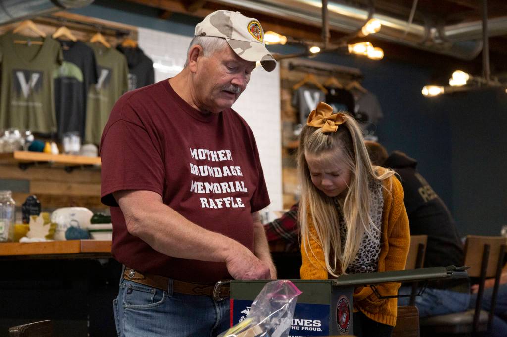 Jim Curtis, left, has Harper Emerson,4, aid him during a raffle drawing on Nov. 10 at Volition Brewing in North Bend. It happened during the Ocean Warriors Birthday Party. Staff photo/Ashley Hiruko