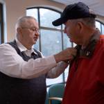 After a quick chat in the waiting room of the American Lake VA Medical Center, Jim Curtis, right, is given a small American flag pin by a fellow veteran. Curtis was there drawing attention to his fundraising efforts. Staff photos / Ashley Hiruko