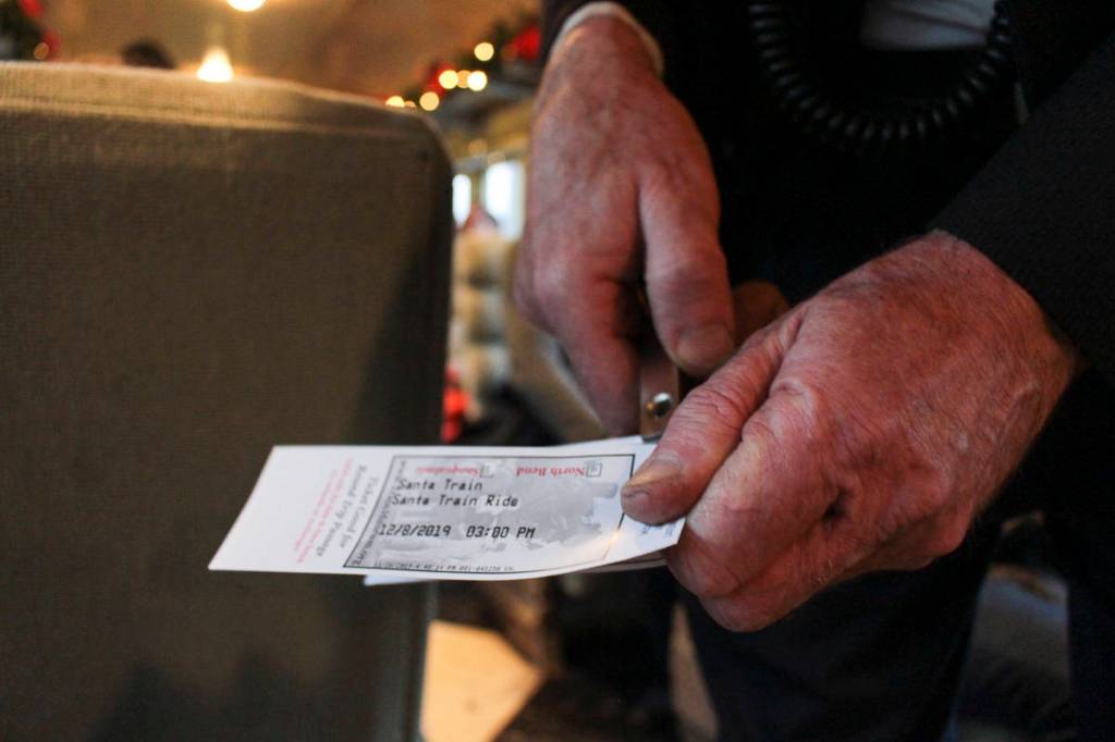 atalie DeFord/staff photo                                The conductor punches the tickets for those who board the Santa Train at the North Bend Depot.