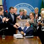 Washington Gov. Jay Inslee (center) shakes hands after he signed a two-year state operating budget on June 30, 2017, at the Capitol in Olympia. (AP Photo/Ted S. Warren, file)