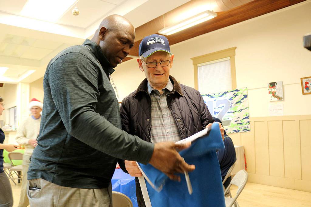 Seahawks legend Alonzo Mitz signs Herb Altmanns 12s flag at Sno-Valley Senior Center on Dec. 13. Stephanie Quiroz/staff photo