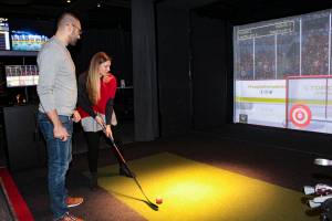 Bellevue residents Marko and Karla Ilicic play a hockey game in the Topgolf Swing Suite inside Forum Social House. Natalie DeFord/staff photo