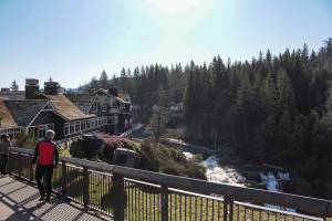 Natalie DeFord/Staff photo. Passersby enjoy a sunny days view of Snoqualmie Falls and the Salish Lodge Spa.