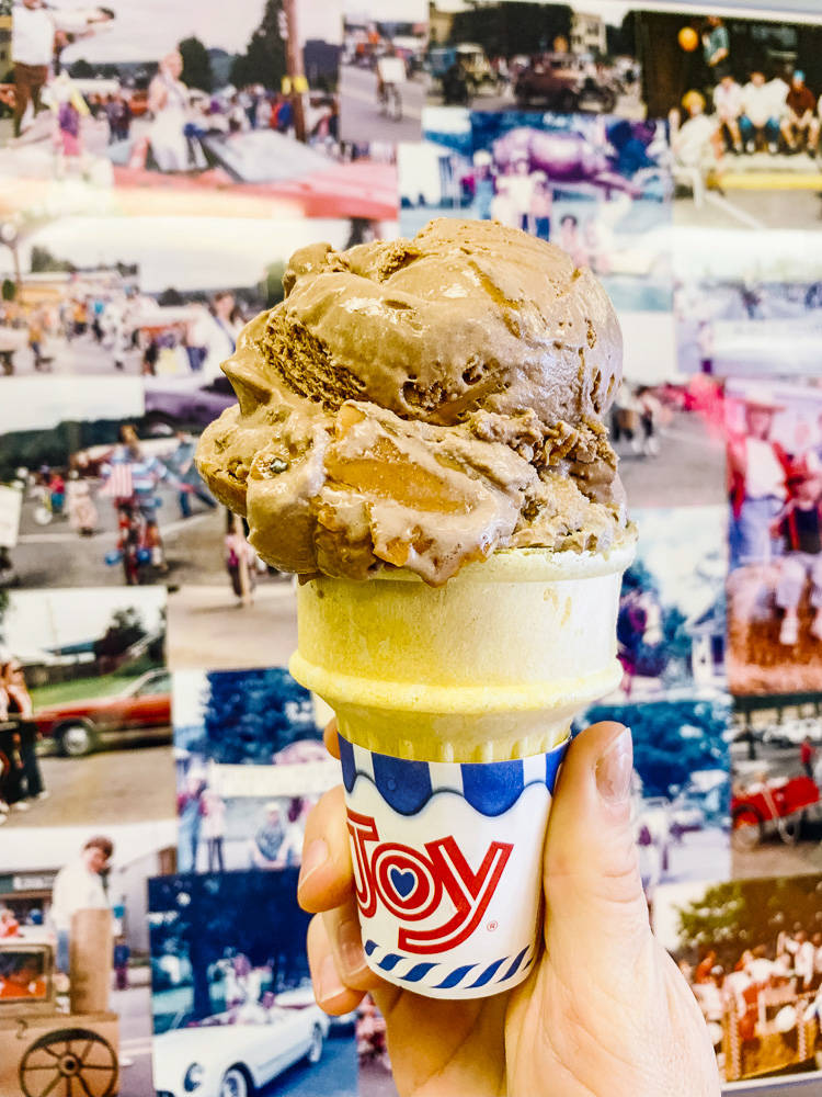 Courtesy photo. A big scoop of ice cream in front of a wall collage of photos through the years at Blakes Pizzeria in Carnation.