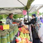 Customers buy vegetables at the North Bend Farmers Market opening day in 2019. File photo