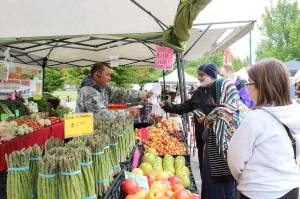 Customers buy vegetables at the North Bend Farmers Market opening day in 2019. File photo