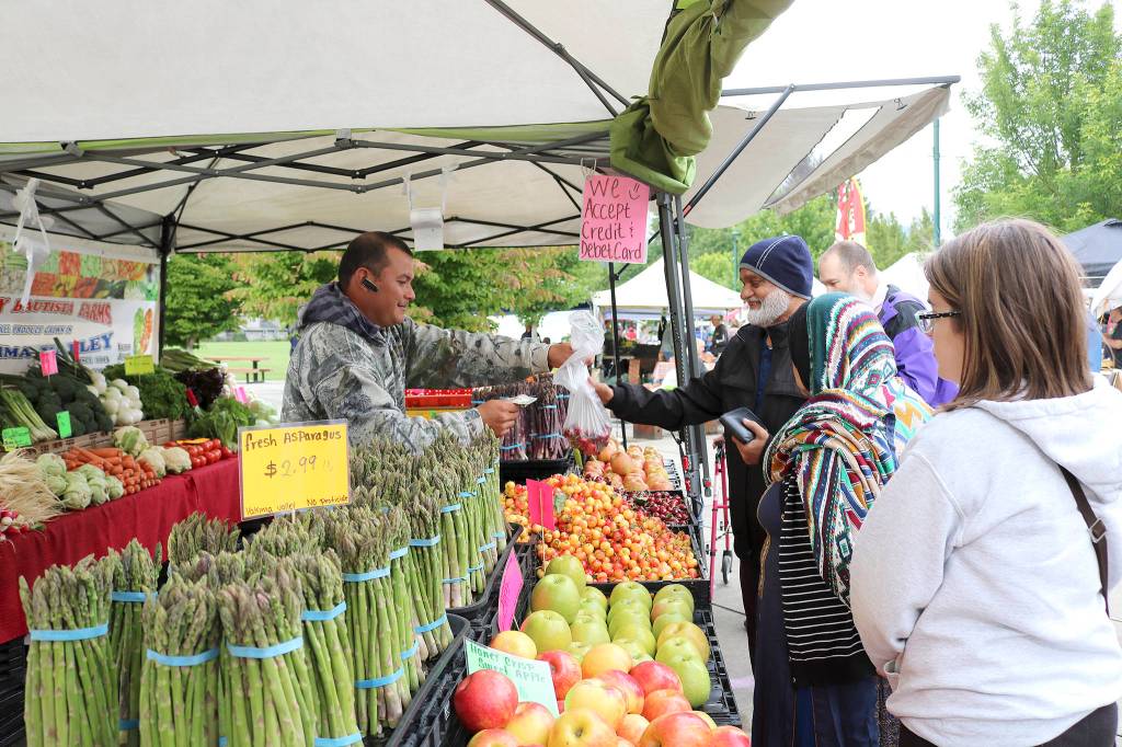 Customers buy vegetables at the North Bend Farmers Market opening day in 2019. File photo
