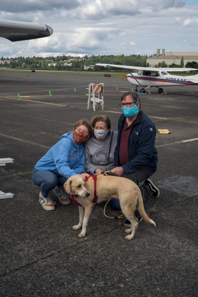 Niaya with her new family meet for the first time at Renton Municipal Airport. The labrador-beagle mix travelled thousands of miles to meet her new family in the midst of the coronavirus pandemic. Photo by Andre Osorio/For the Renton Reporter