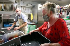 Brian Tilley (left) and Katie Dearman work the wash station Friday at Kates Greek American Deli in Everett. (Kevin Clark / The Herald)