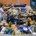 Tony Mandeville places a bouquet of flowers on the windshield of a Bothell Police Department vehicle that was turned into a memorial Tuesday in front of Bothell City Hall. (Olivia Vanni / The Herald)
