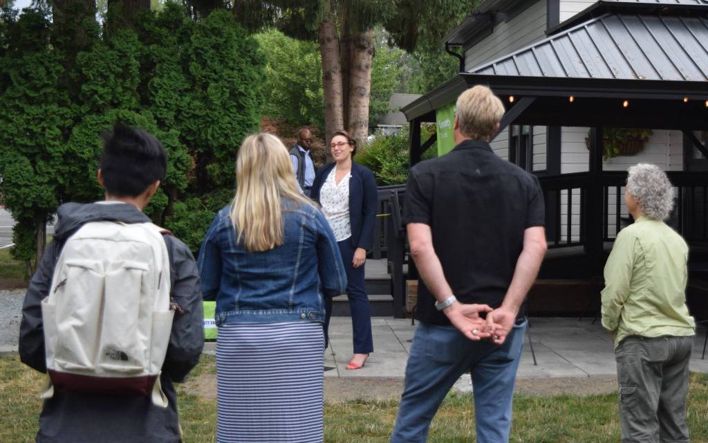 A crowd listens to Angela Donaldson, president of the Fall City Community Association, give a speech about the new grant program, outside Aroma Coffee in Fall City.