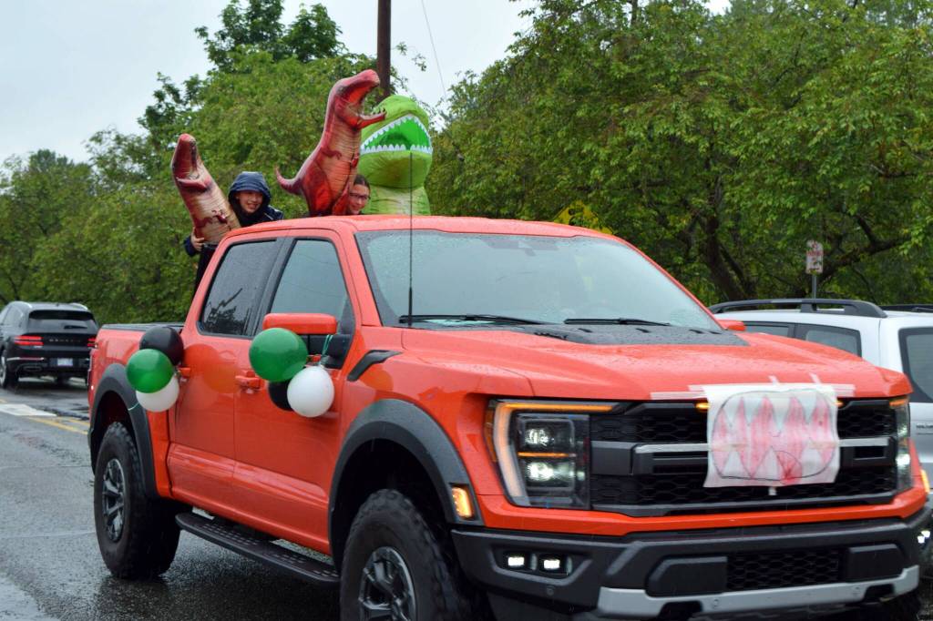 Students with dinosaurs drive by during the Fall City Graduate Parade. Photo Conor Wilson/Valley Record.