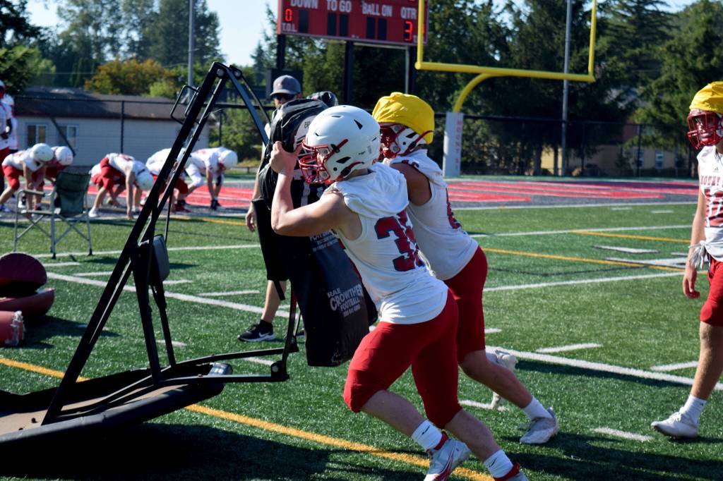 Wildcats hit blocking sleds during the first day of practice Aug. 17. Below, Senior Cyrus Turley looks downfield for a receiver.