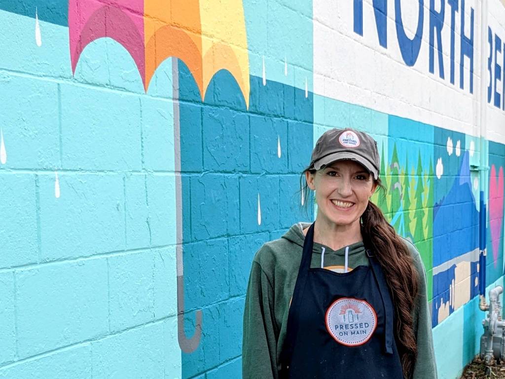 Hayley Raff, owner of Pressed on Main, poses in front of a mural on the side of her business at 208 Main Ave. S., North Bend. Photo by Conor Wilson/Valley Record
