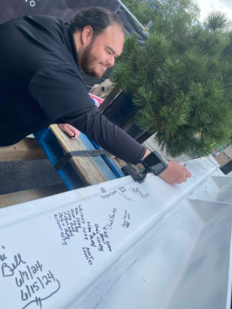 Tribal member and Fireweed Cannabis Manager Robbie de los Angeles signing the beam. (Photo by Bill Shaw/Valley Record)