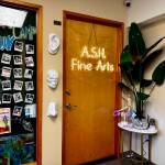The front door of ASH Fine Arts, adorned with a neon sign and photos of classes. (Grace Gorenflo/Valley Record)