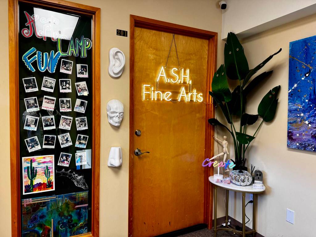 The front door of ASH Fine Arts, adorned with a neon sign and photos of classes. (Grace Gorenflo/Valley Record)