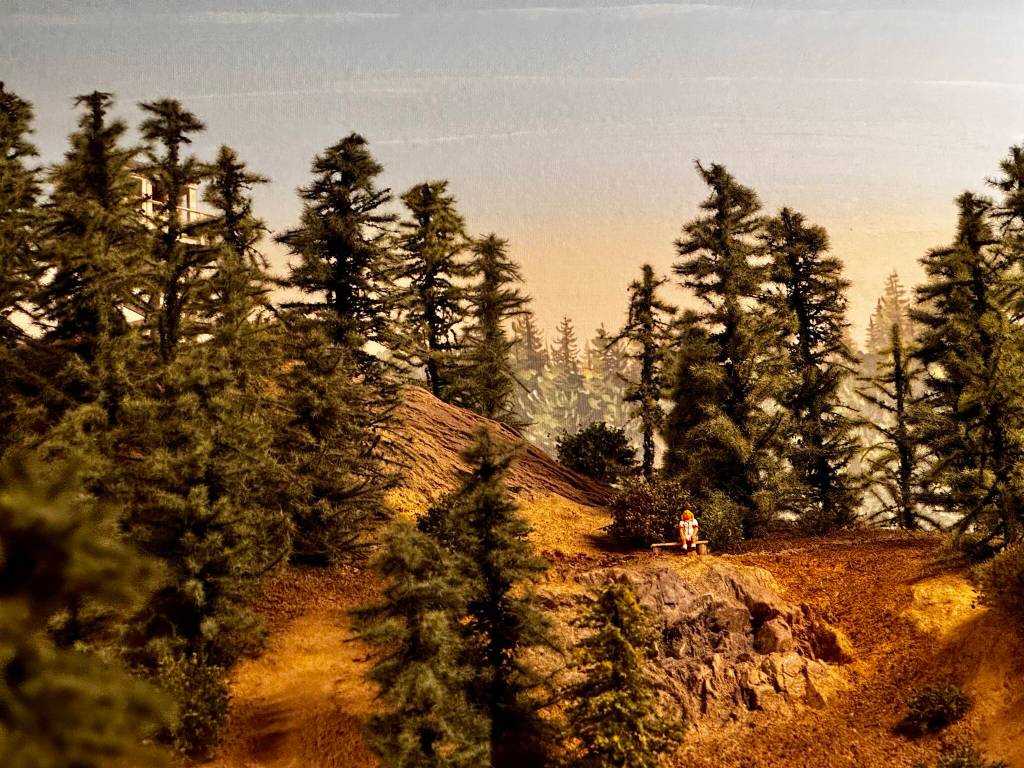 Pacific West Rails model train display shows a woman sitting on a bench in the mountains. (Grace Gorenflo/Valley Record)