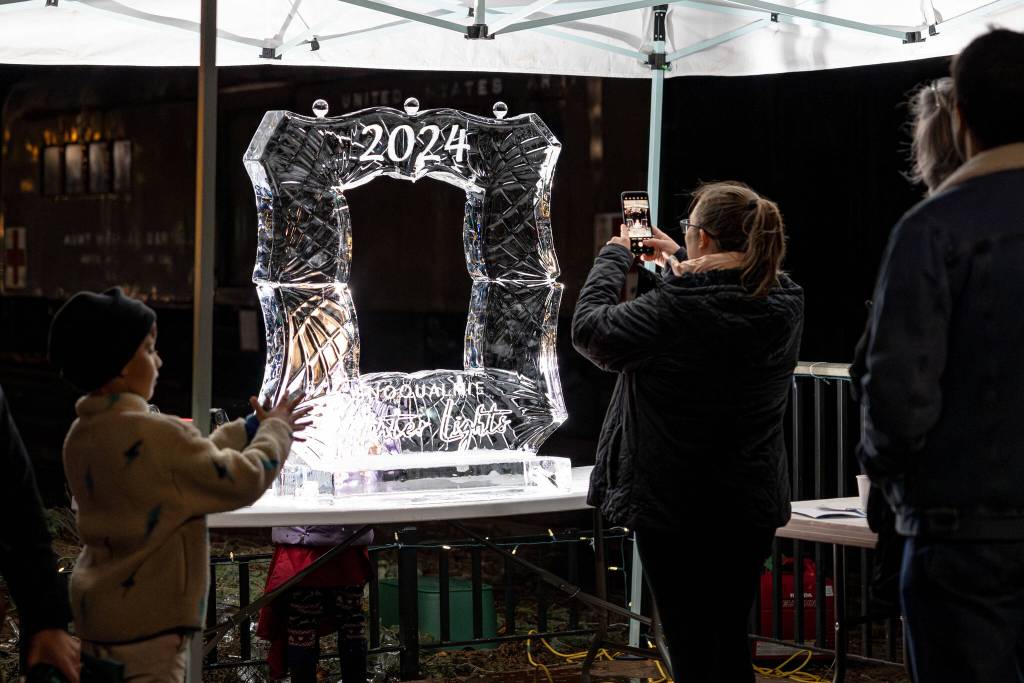 Visitors take photos of the ice sculpture at the Snoqualmie Winter Lights celebration on December 7, 2024, in Snoqualmie, Washington.