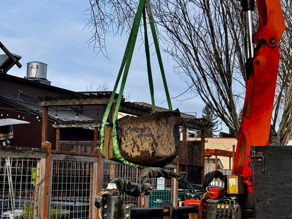 A Marenakos Rock Center employee lowers the bird bath into its new home at Down to Earth.
