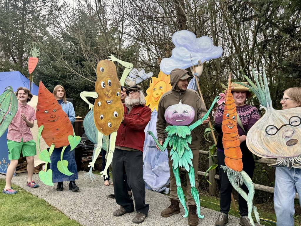 A group of volunteers line up as the March of the Vegetables at Depot Park on Saturday, March 30. Artist Paula Strobel made the vegetable figures with cardboard and paint. (File photo)