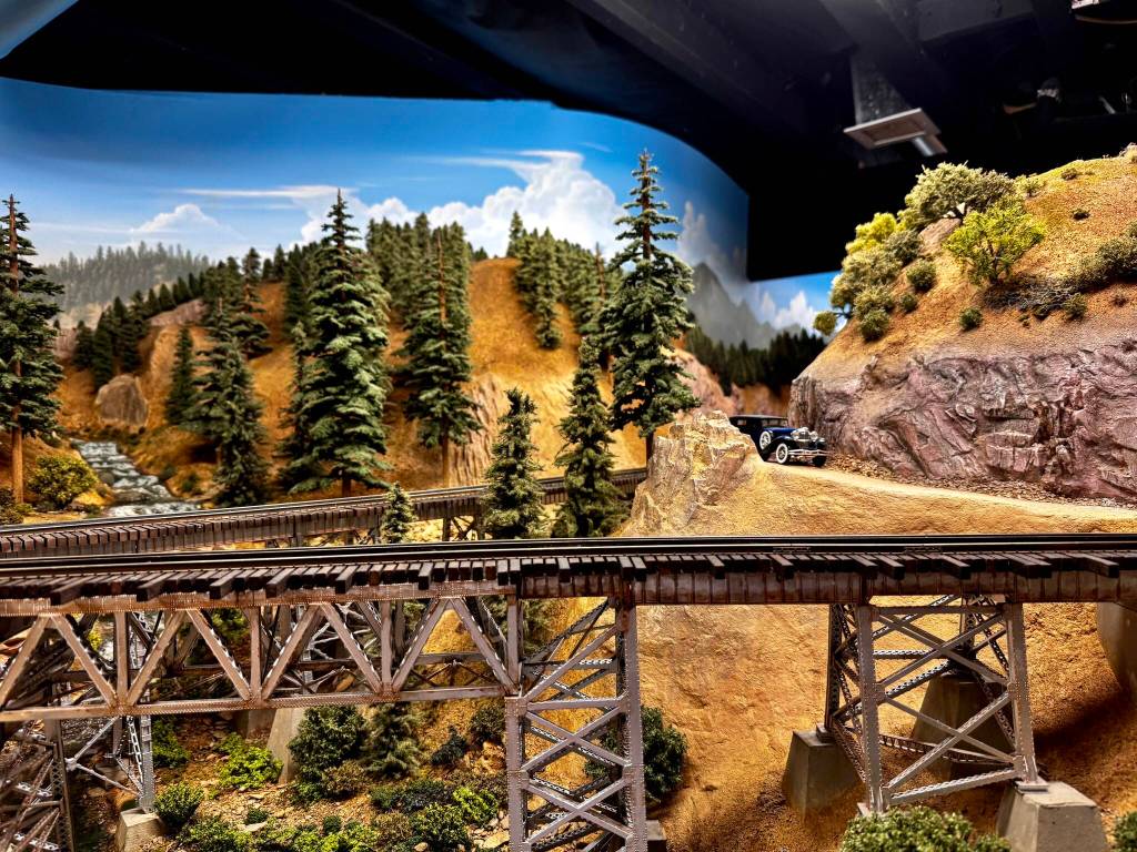 A 1930s-era car sits on a mountain road in the Pacific West Rail model train display. Grace Gorenflo/Valley Record