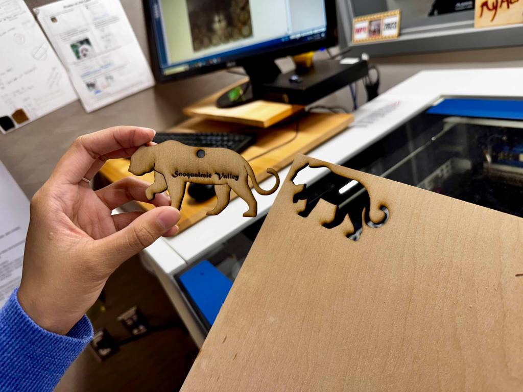 Romalyn Hatol, a junior at Mount Si High School, shows the finished product after laser-cutting a wood cougar ornament. (Grace Gorenflo/Valley Record)