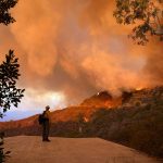 A firefighter stands against a backdrop of wildfire in California. Photo courtesy of the Fall City Fire Department