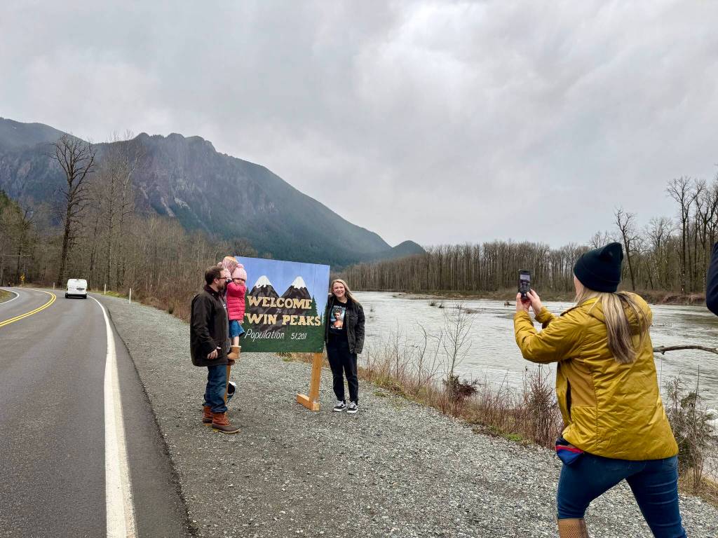 Jessica Self, executive director of the North Bend Downtown Foundation, snaps a photo of the Daniel family with the Welcome to Twin Peaks sign, Feb. 24, 2025. The family came to Real Twin Peaks weekend from Alabama.