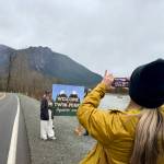 Jessica Self, executive director of the North Bend Downtown Foundation, snaps a photo of fans posing with the Welcome to Twin Peaks sign, Feb. 24, 2025.