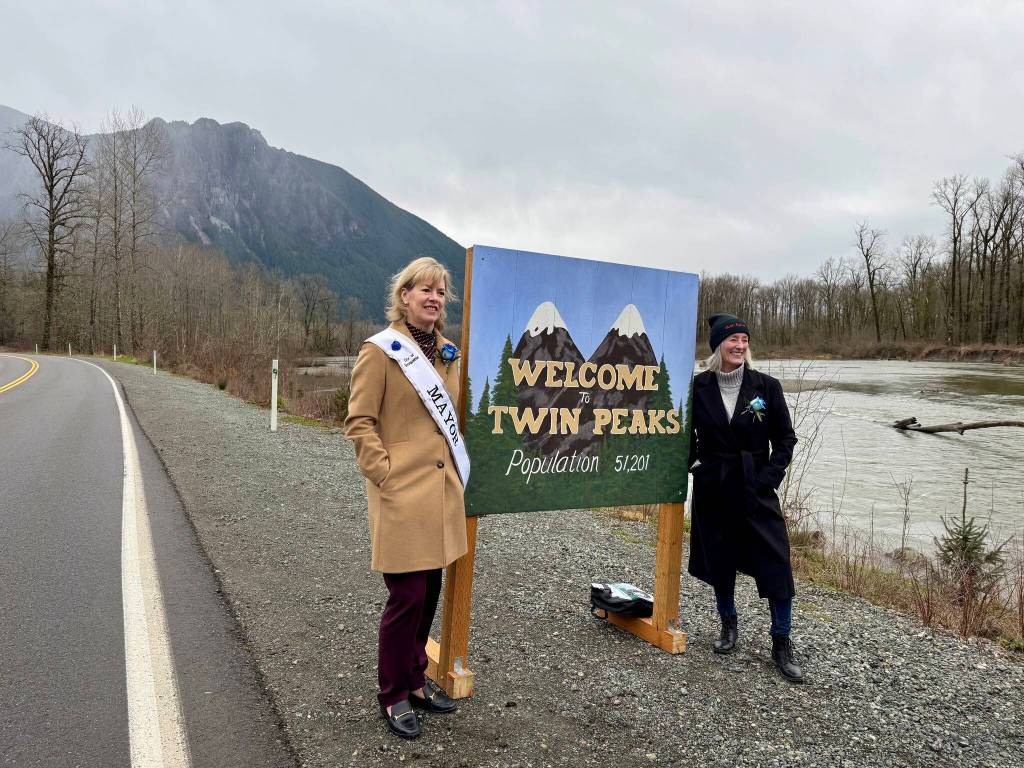 Snoqualmie Mayor Katherine Ross (left) and North Bend Mayor Mary Miller stand for a photo with the Welcome to Twin Peaks sign, Feb. 25, 2025.