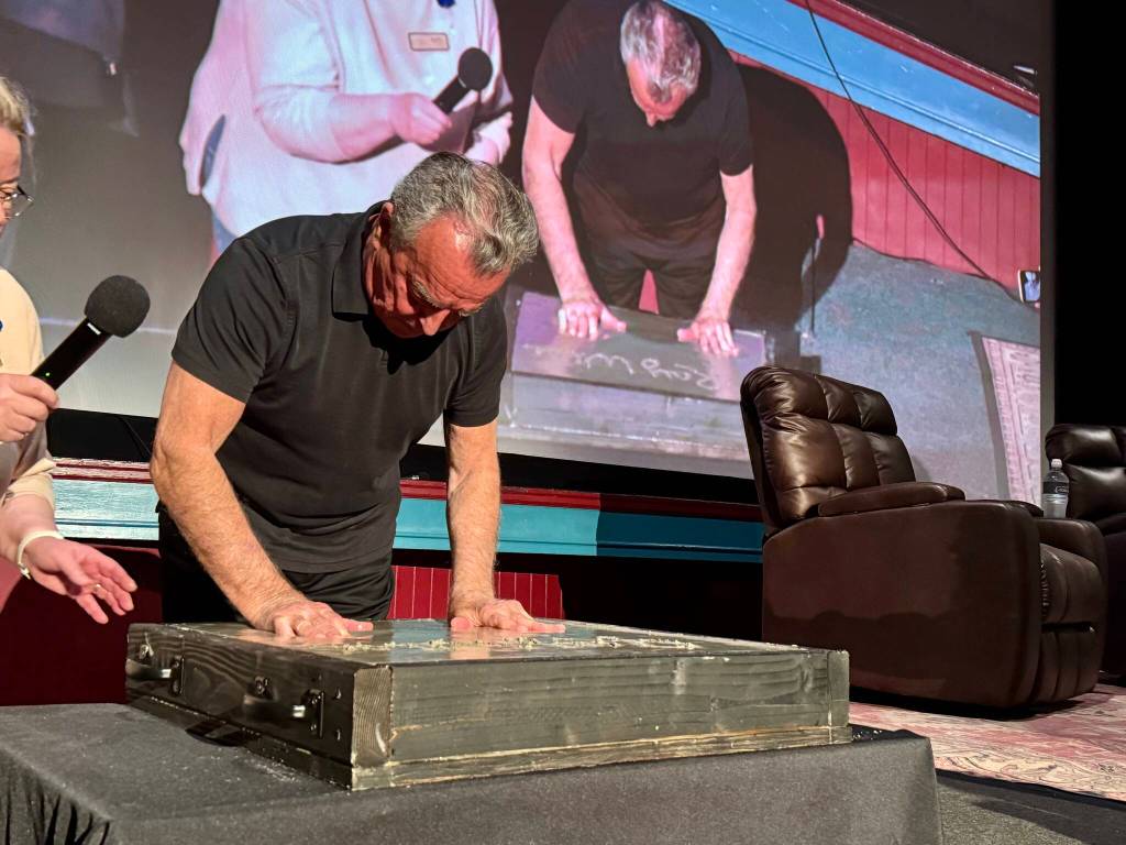 Actor Ray Wise, who played Leland Palmer in Twin Peaks, imprints his hands in a block of wet concrete at the North Bend Theatre, Feb. 22, 2025. The concrete block will be added to the sidewalk outside the theater. (Grace Gorenflo/Valley Record)