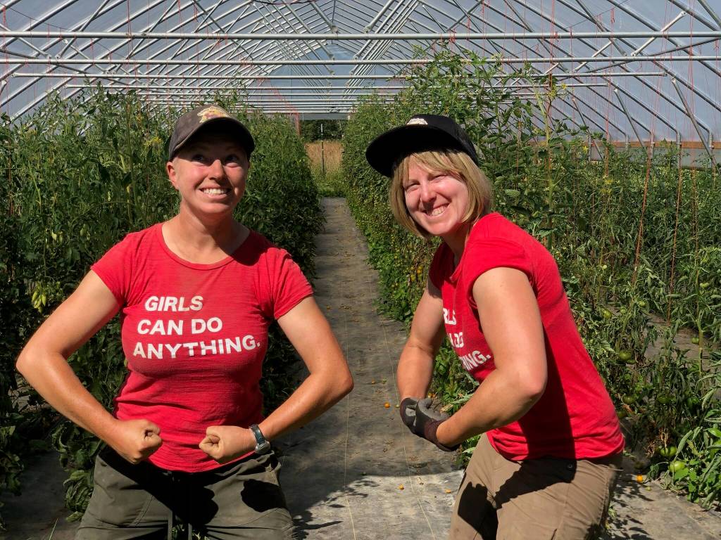 Owners of Frisky Girl Farm Ashley Wilson (left) and Ellen Scheffer stand for a photo in their greenhouse. Photo courtesy of Frisky Girl Farm
