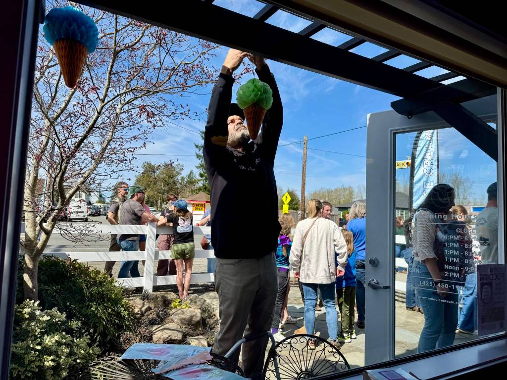 Owner Larry Brown hangs ice cream cone decorations outside Mooo! Ice Cream during its grand opening April 5, 2025. Grace Gorenflo/Valley Record