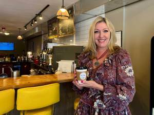 Tonya Guinn, co-founder of The Trail Youth Coffee Home, holds a coffee cup with one of the shops signature positive stickers on it April 11, 2025. Grace Gorenflo/Valley Record