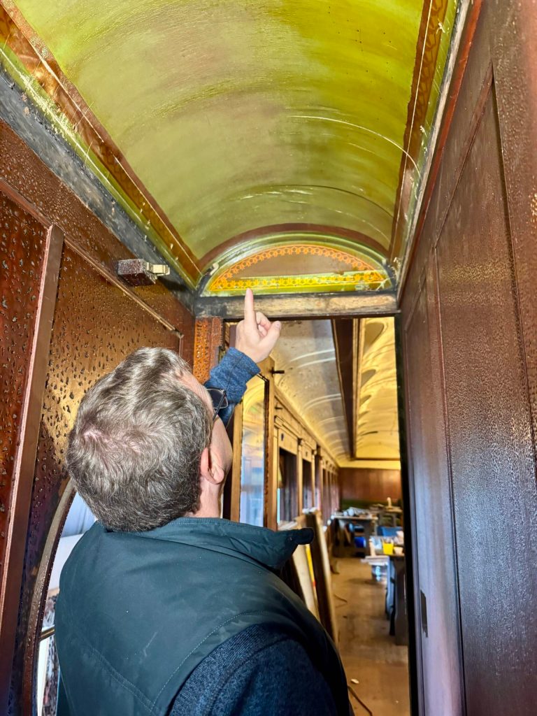 Northwest Railway Museum Executive Director Richard Anderson points to an original piece of ceiling in parlor car 1049, April 29, 2025. (Grace Gorenflo/Valley Record)