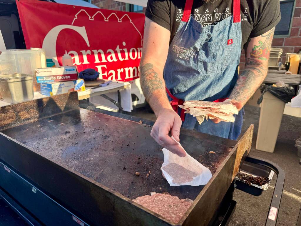 Carnation Farms butcher Thomas Coss cooks up smash burgers at the opening of the Millers outdoor venue, July 3, 2025.